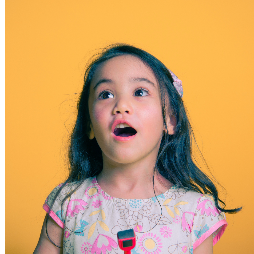 A girl looking at a toy in awe with an expression of excitement and amazement